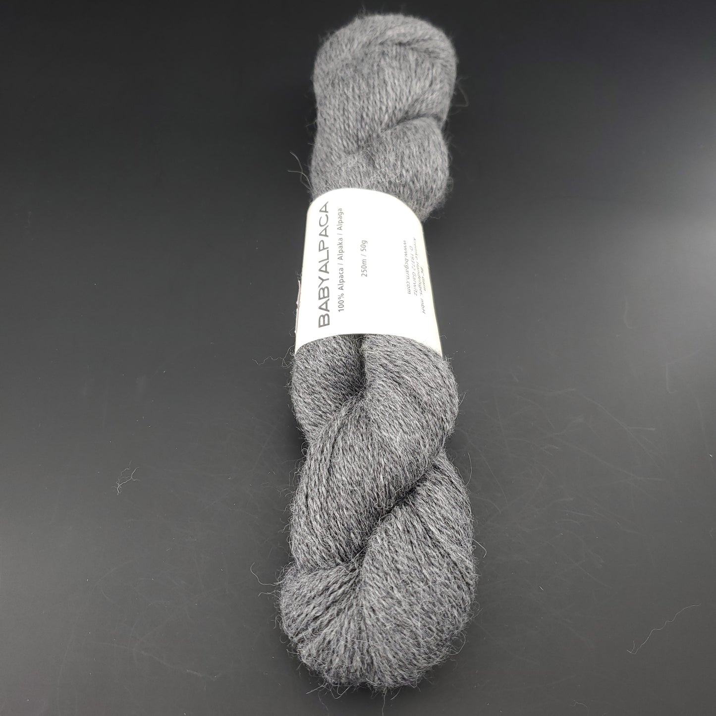 Echeveau de laine Baby Alpaca de BC Garn de couleur 132 dark grey melange sur fond noir.