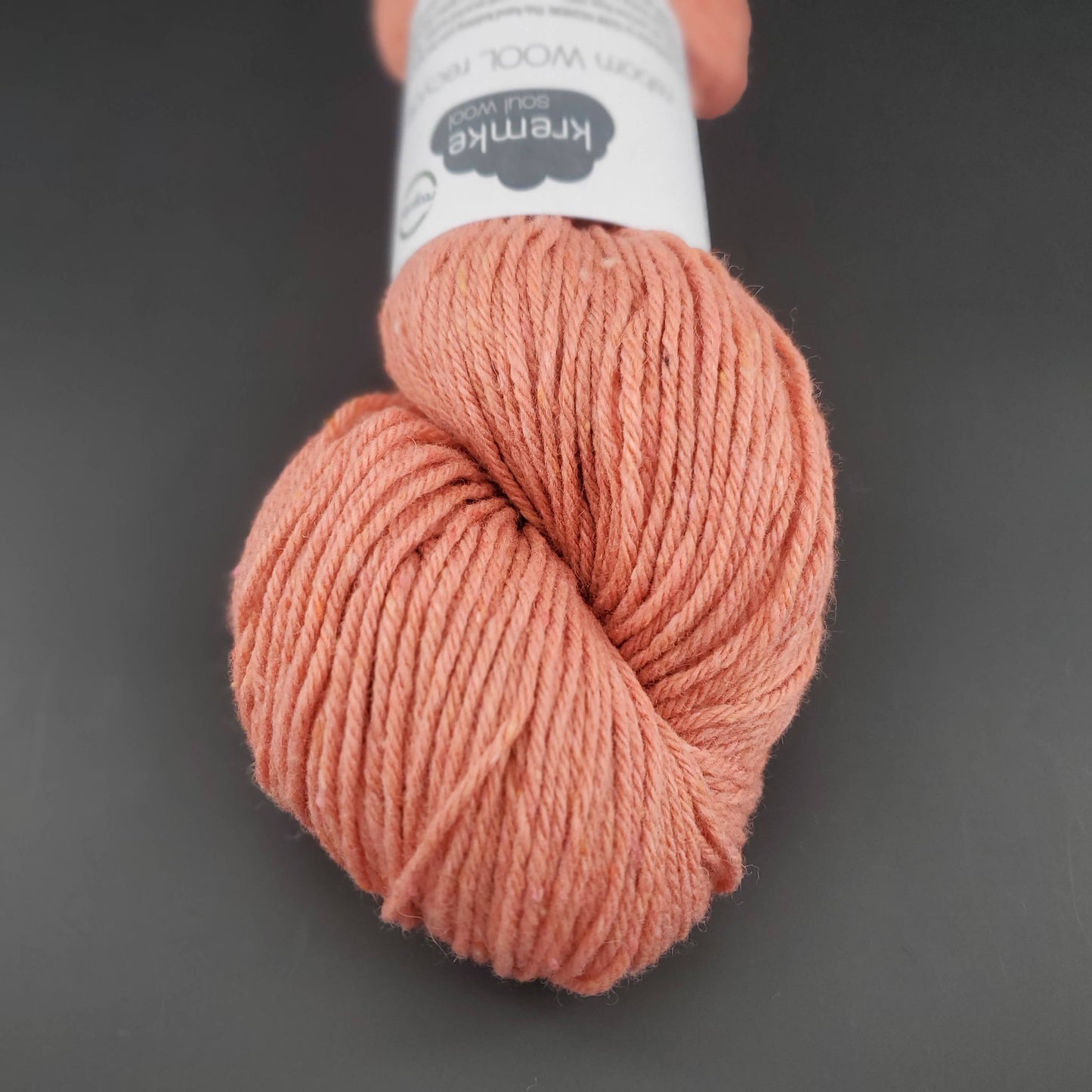 Echeveau de laine Kremke Reborn Wool de couleur 04 light orange, sur fond noir, pour tricot et crochet.