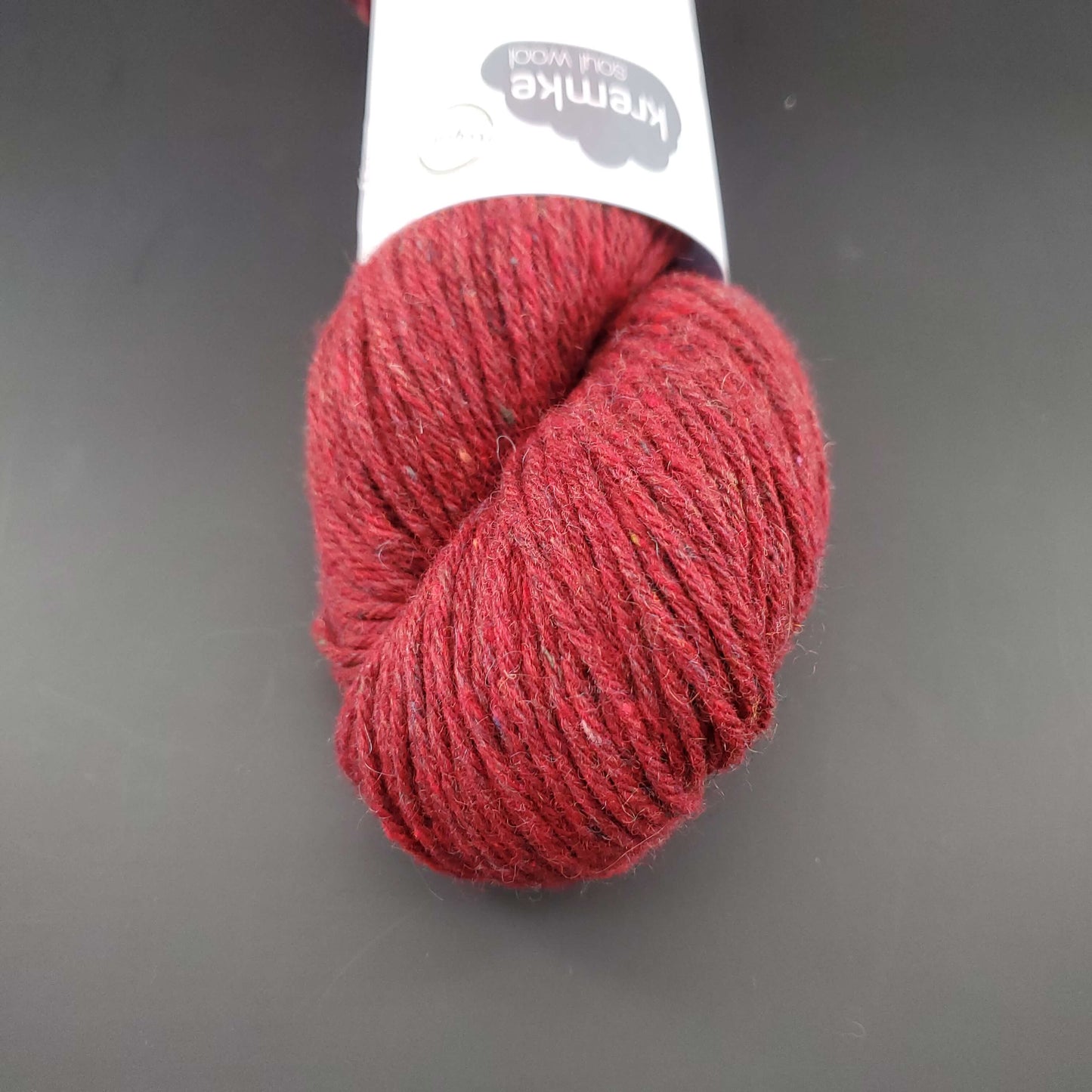 Echeveau de laine Kremke Reborn Wool de couleur 09 cherry melange, sur fond noir, pour tricot et crochet.