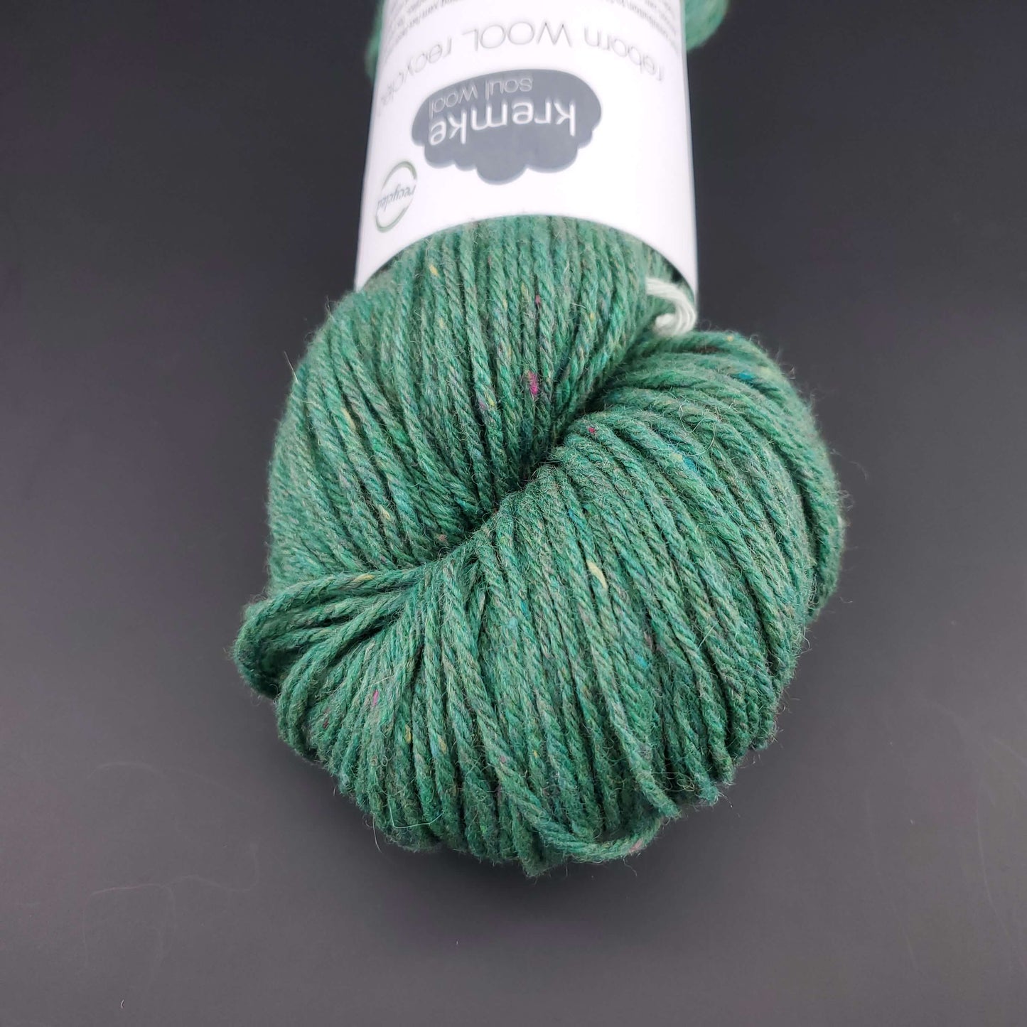 Echeveau de laine Kremke Reborn Wool de couleur 11 emerald, sur fond noir, pour tricot et crochet.