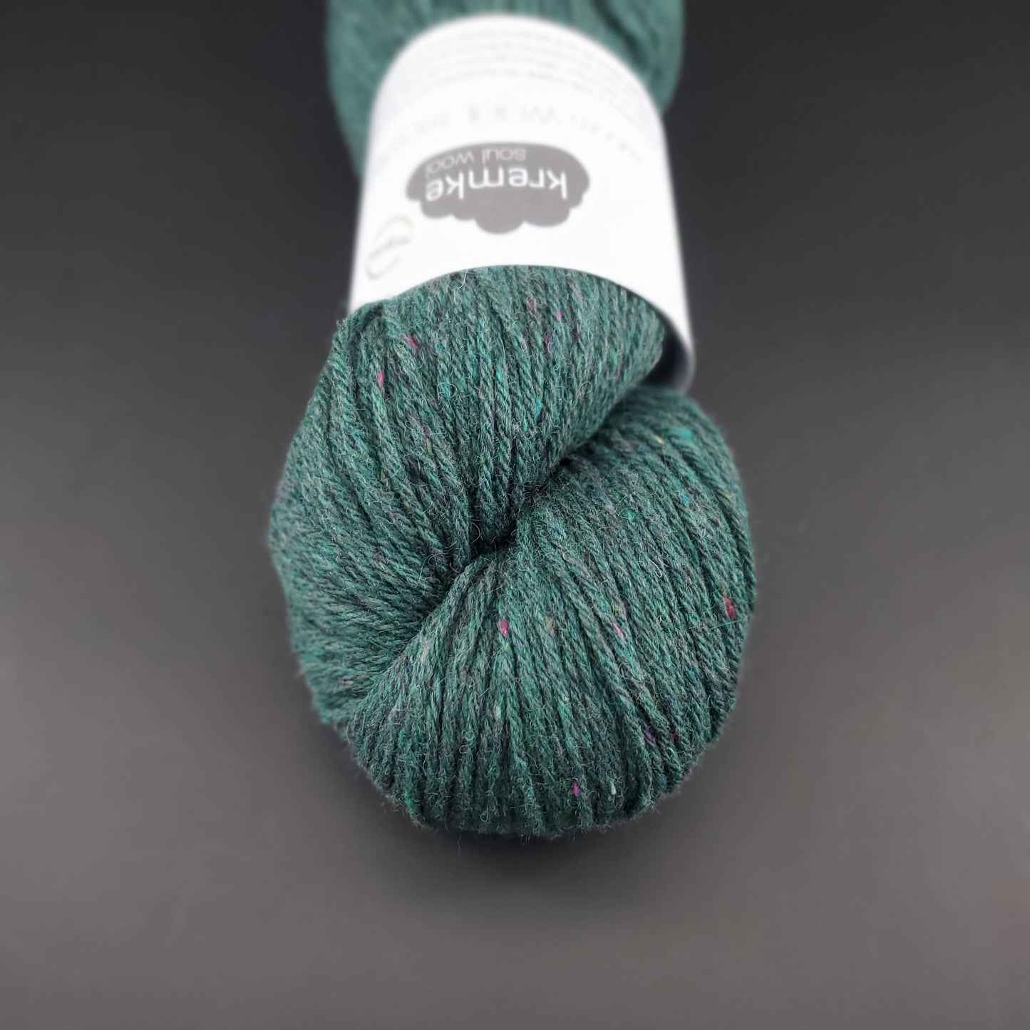 Echeveau de laine Kremke Reborn Wool de couleur 12 dark green, sur fond noir, pour tricot et crochet.