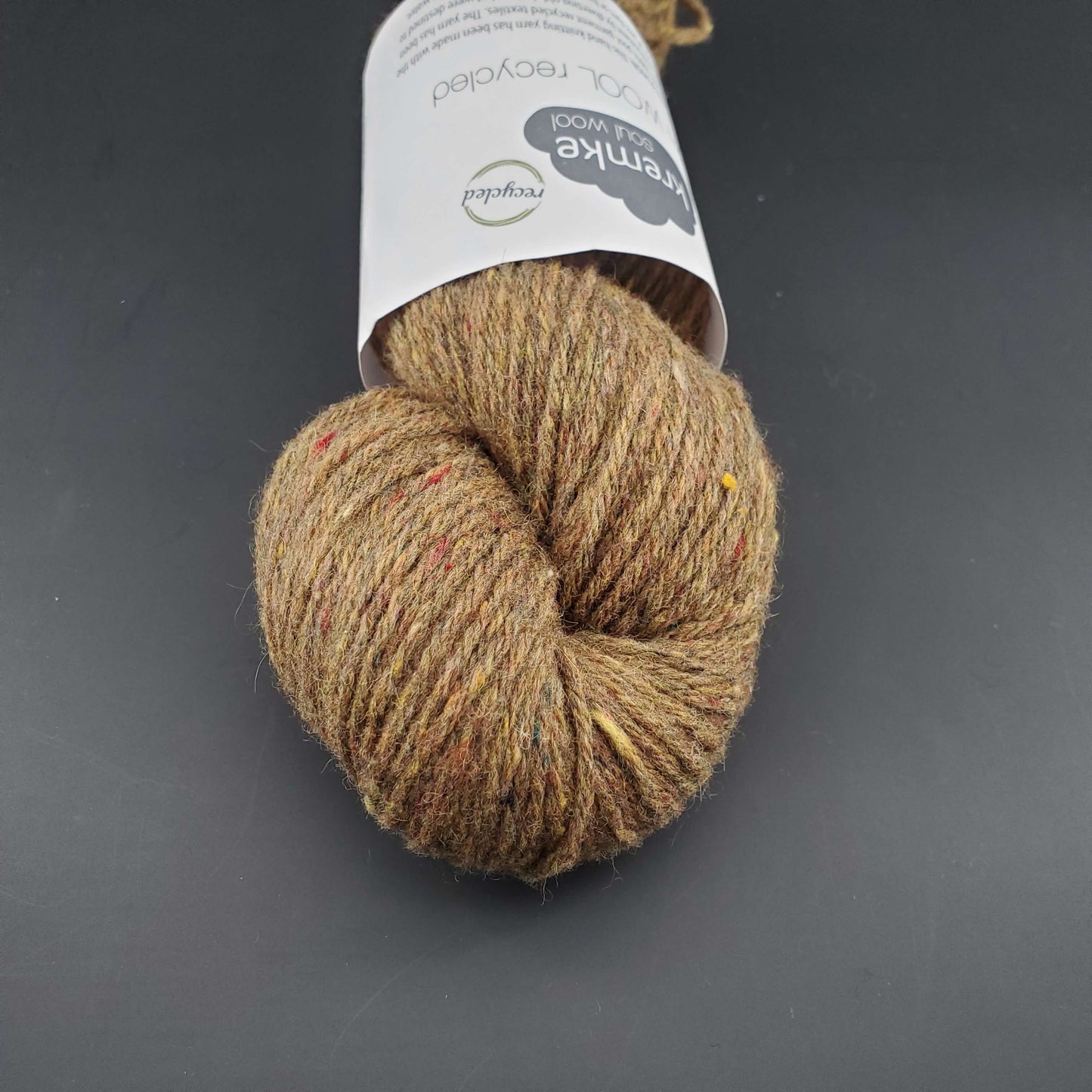 Echeveau de laine Kremke Reborn Wool de couleur 14 bras melange, sur fond noir, pour tricot et crochet.