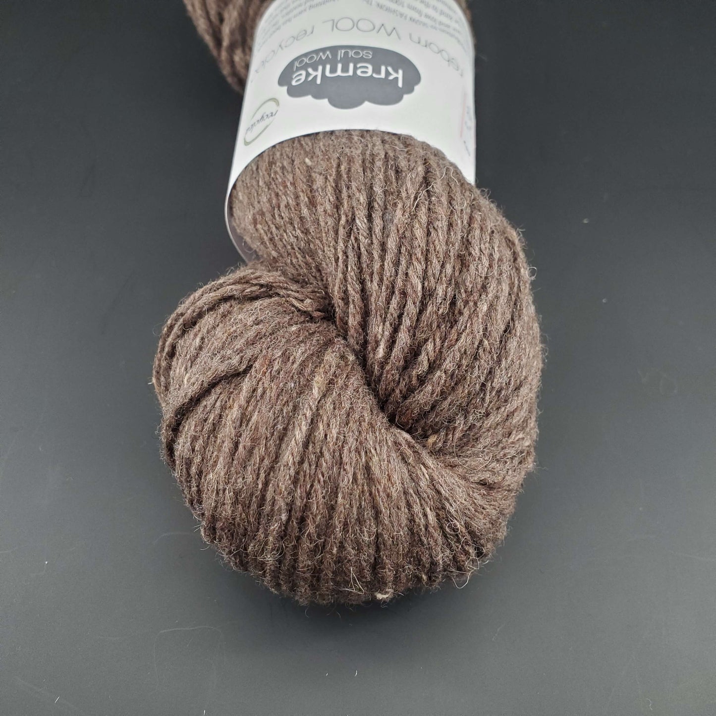 Echeveau de laine Kremke Reborn Wool de couleur 17 chestnut melange, sur fond noir, pour tricot et crochet.