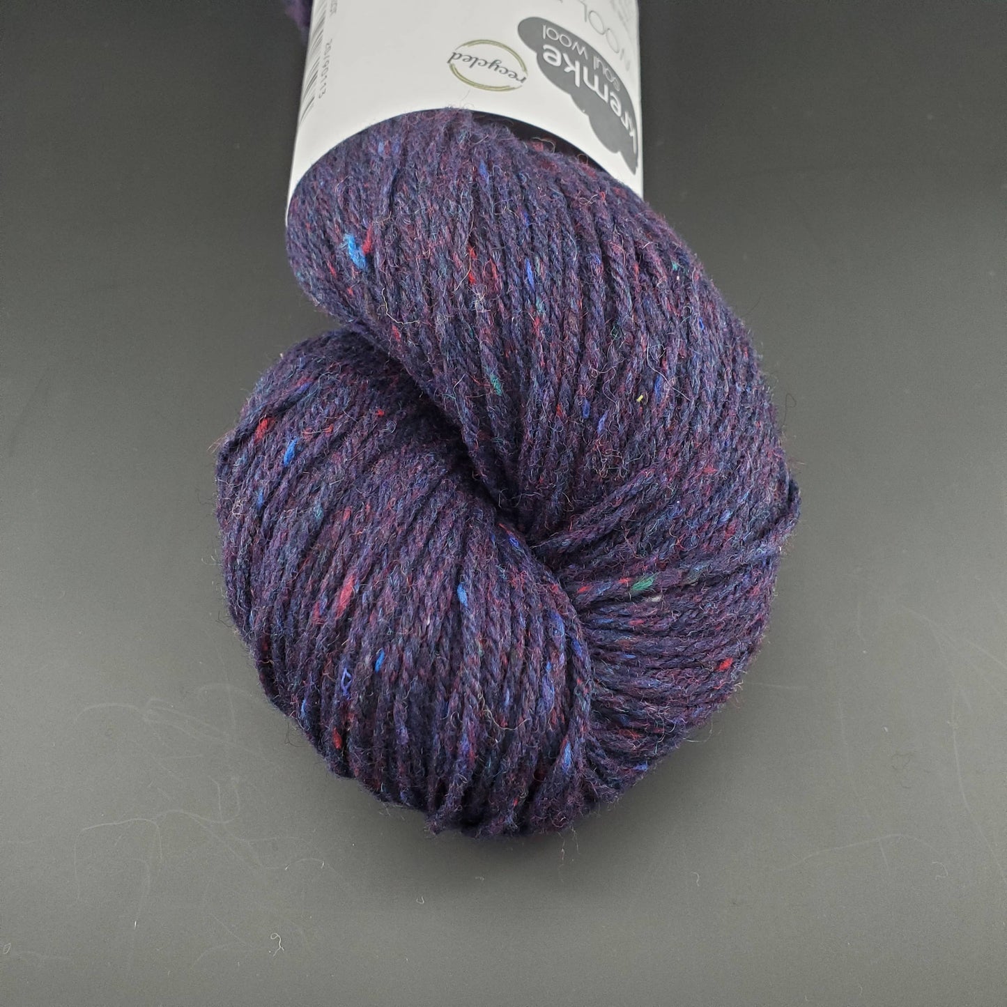 Echeveau de laine Kremke Reborn Wool de couleur 20 indigo melange, sur fond noir, pour tricot et crochet.