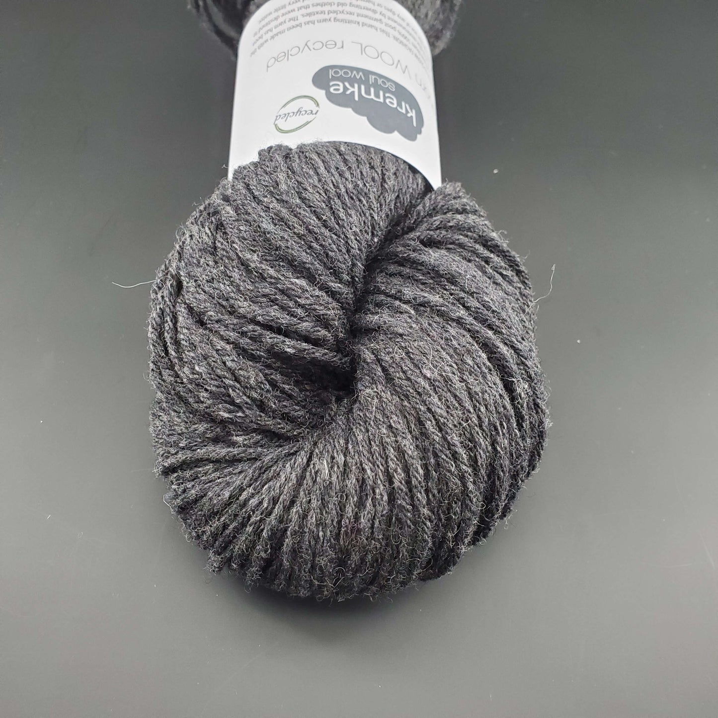 Echeveau de laine Kremke Reborn Wool de couleur 23 steel gray, sur fond noir, pour tricot et crochet.