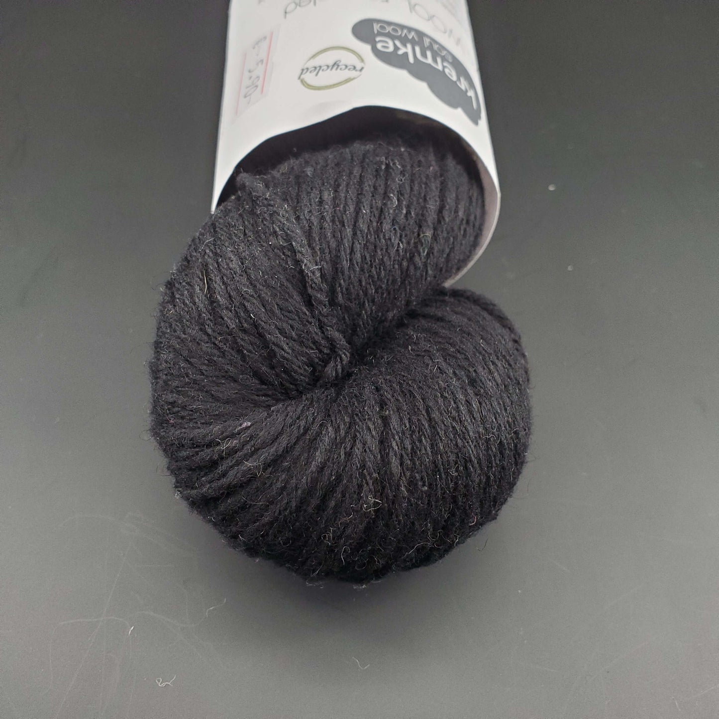 Echeveau de laine Kremke Reborn Wool de couleur 24 black, sur fond noir, pour tricot et crochet.