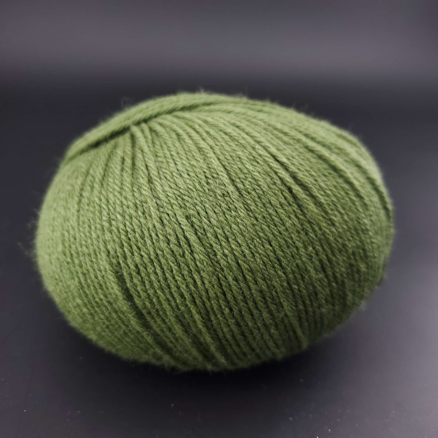 Pelote de laine the merry merino 220 de kremke coloris 33 vert foret sur fond noir