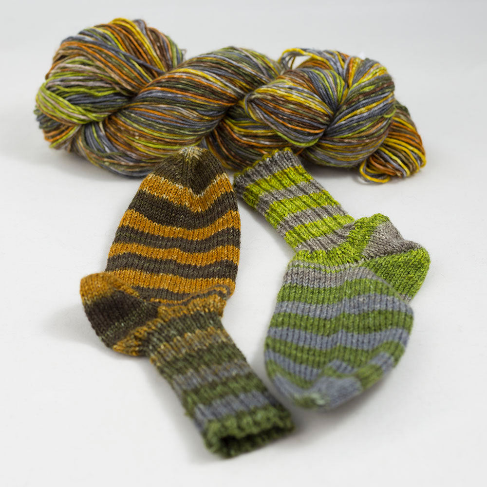 écheveau de laine à chaussettes Lazy Lion, multicolore, marque Kremke et paire de chaussettes tricotées (jaune gris, vert)