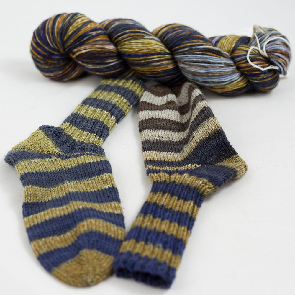 écheveau de laine à chaussettes Lazy Lion, multicolore, marque Kremke et paire de chaussettes tricotées (gris bleu, beige)