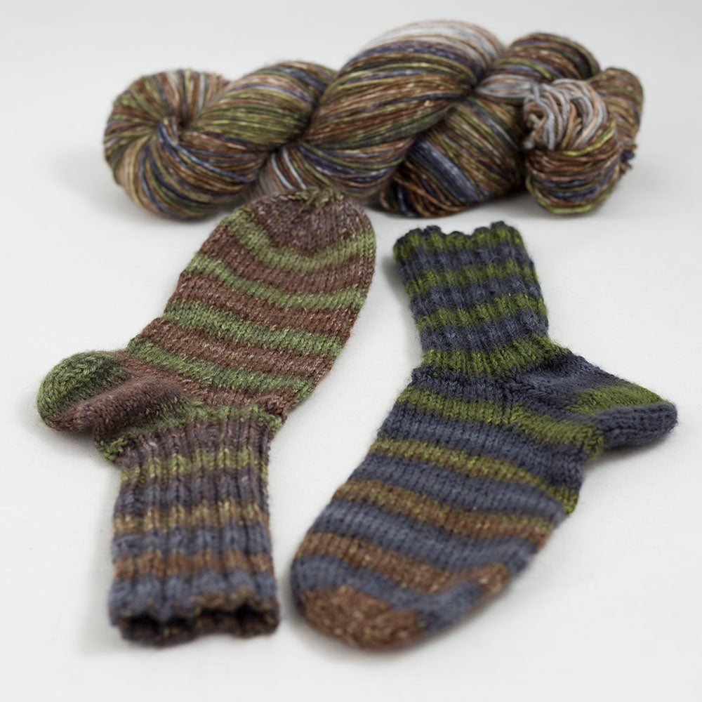 écheveau de laine à chaussettes Lazy Lion, multicolore, marque Kremke et paire de chaussettes tricotées (marron, vert, bleu)