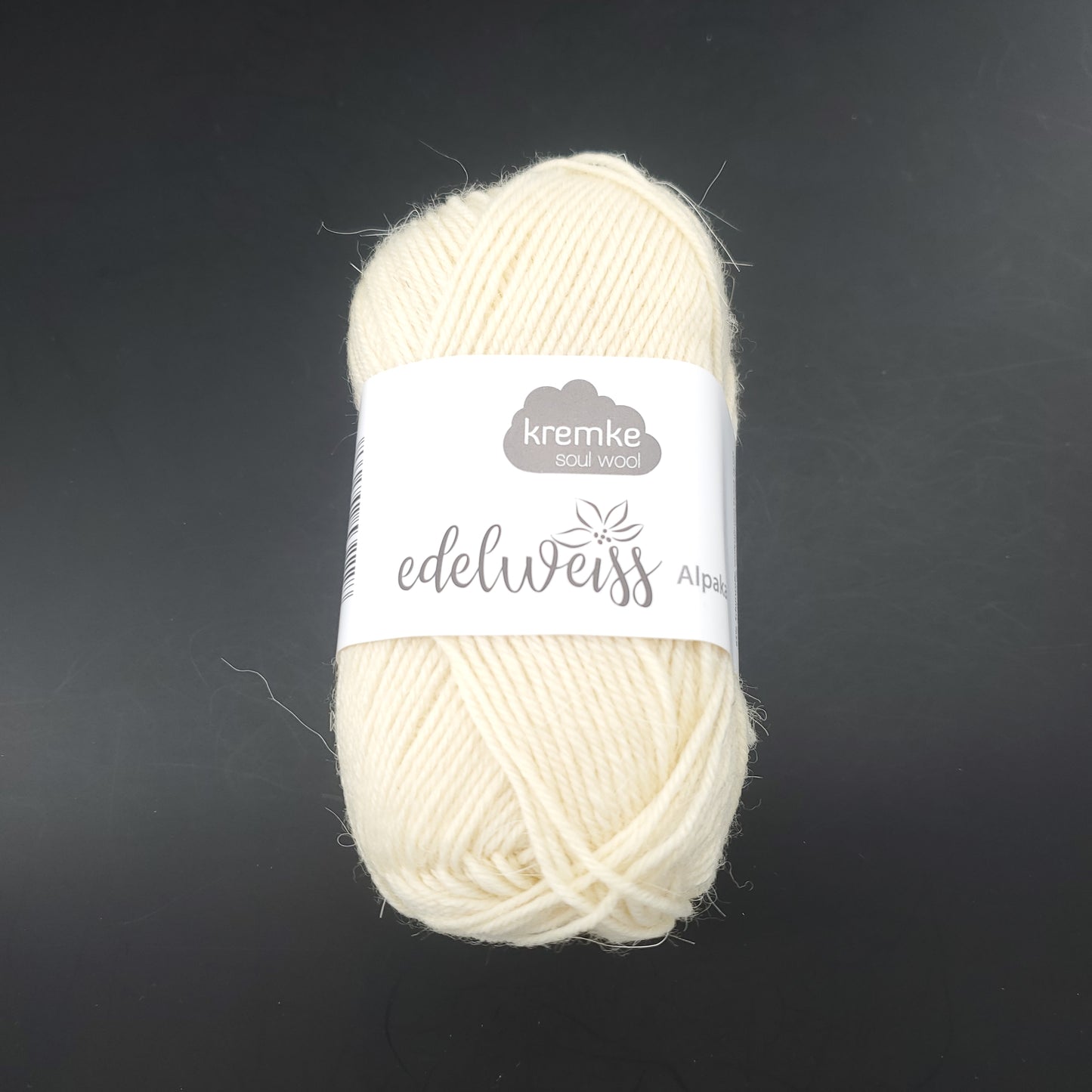 pelote de laine à chaussettes edelweiss alpaka 4ply de marque kremke de couleur 001 pour tricot et crochet sur fond noir