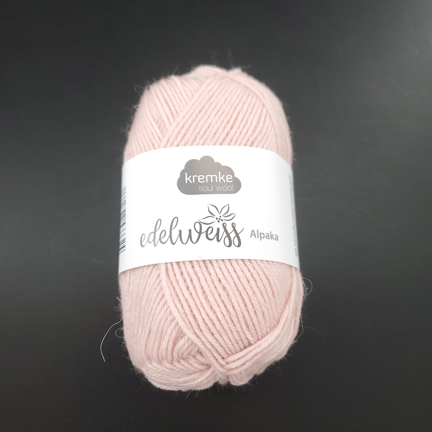 pelote de laine à chaussettes edelweiss alpaka 4ply de marque kremke de couleur 011 pour tricot et crochet sur fond noir