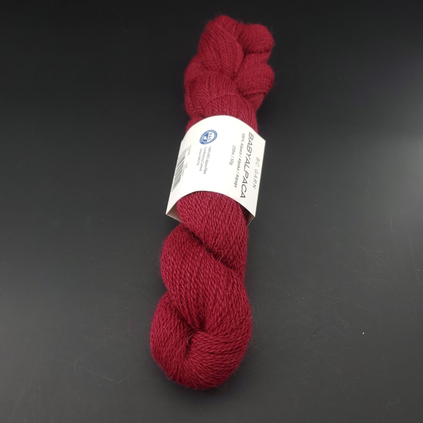 Echeveau de laine Baby Alpaca de BC Garn de couleur 08 wine sur fond noir.
