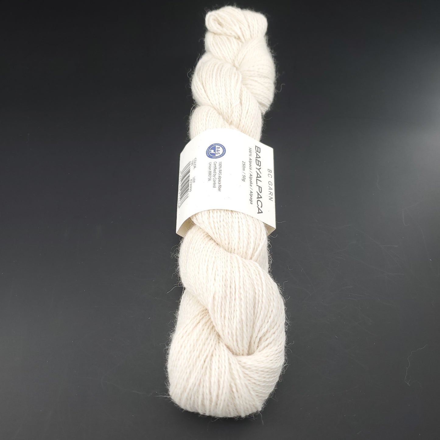 Echeveau de laine Baby Alpaca de BC Garn de couleur 100 natural white sur fond noir.