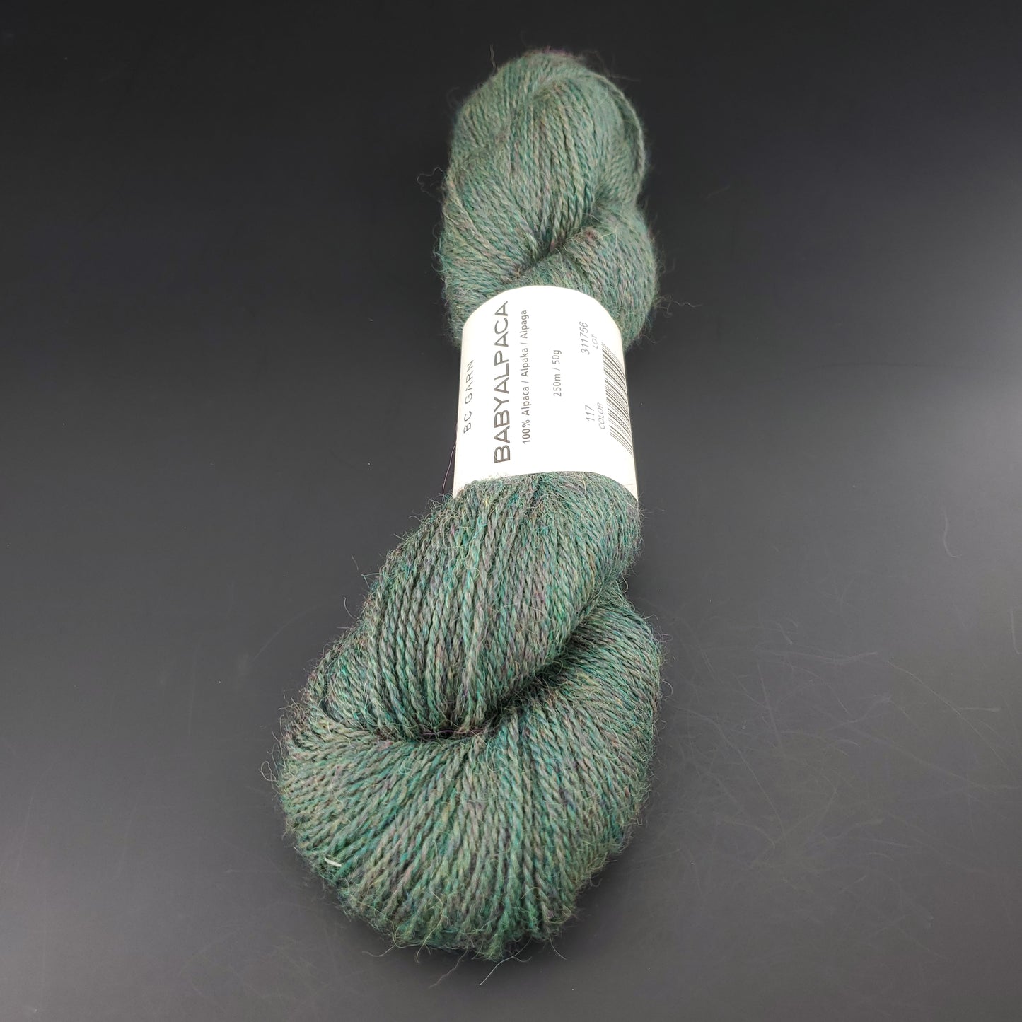 Echeveau de laine Baby Alpaca de BC Garn de couleur 117 woods heather sur fond noir.