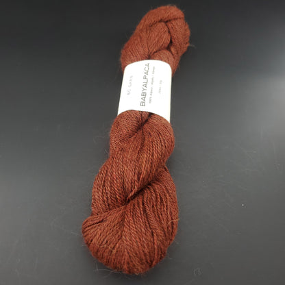Echeveau de laine Baby Alpaca de BC Garn de couleur 125 redbrown melange sur fond noir.