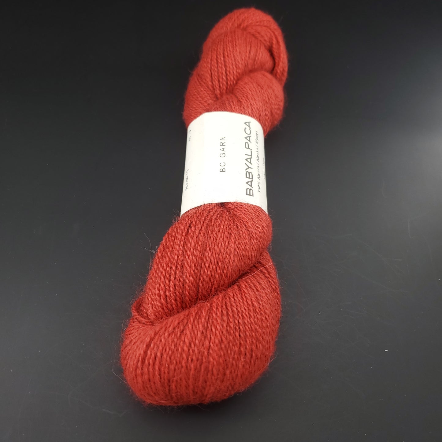 Echeveau de laine Baby Alpaca de BC Garn de couleur 39 brick red sur fond noir.