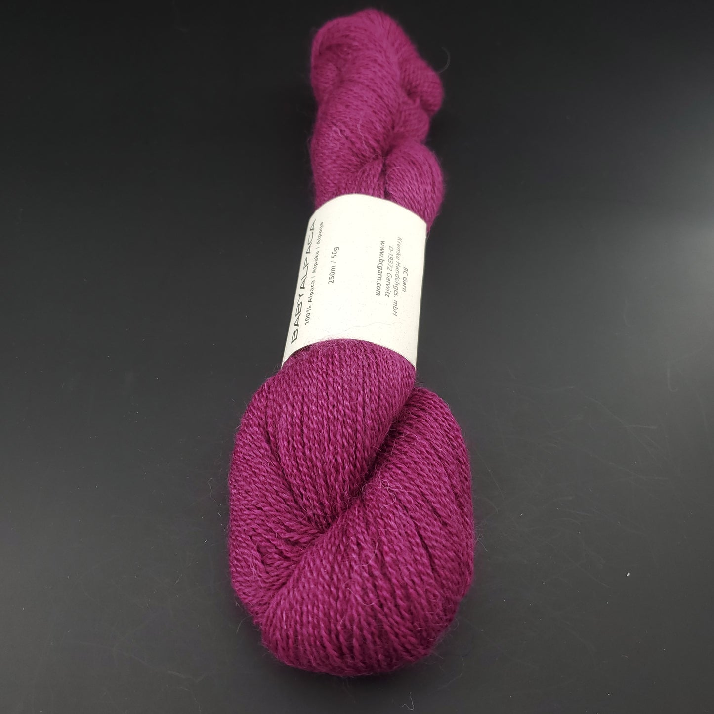 Echeveau de laine Baby Alpaca de BC Garn de couleur 40 plum sur fond noir.