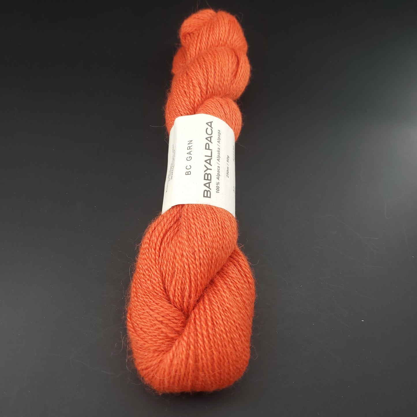 Echeveau de laine Baby Alpaca de BC Garn de couleur 57 orange neon sur fond noir.