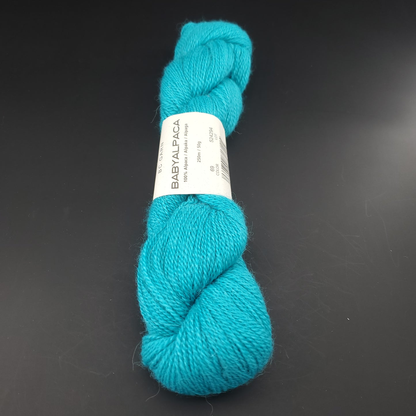 Echeveau de laine Baby Alpaca de BC Garn de couleur 69 intense turquoise sur fond noir.