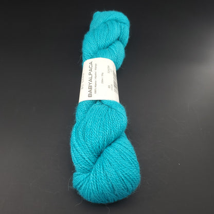 Echeveau de laine Baby Alpaca de BC Garn de couleur 69 intense turquoise sur fond noir.