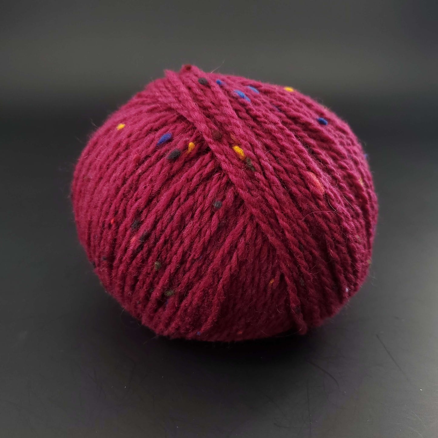 Pelote de laine Fonty Super Tweed de couleur violet foncé sur fond noir