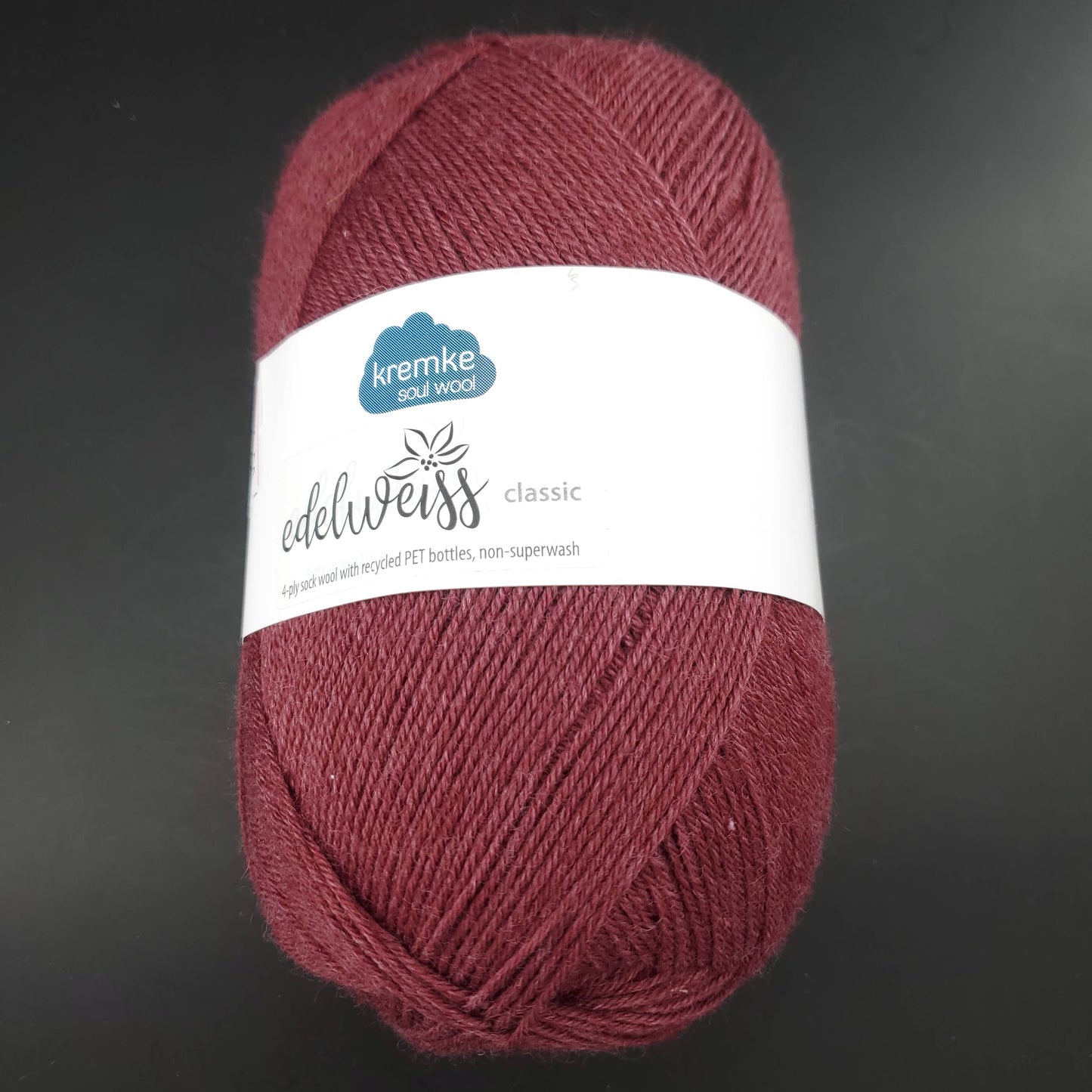 pelote de laine edelweiss classic de marque kremke de coloris 406 pourpre pour tricot et crochet sur fond noir