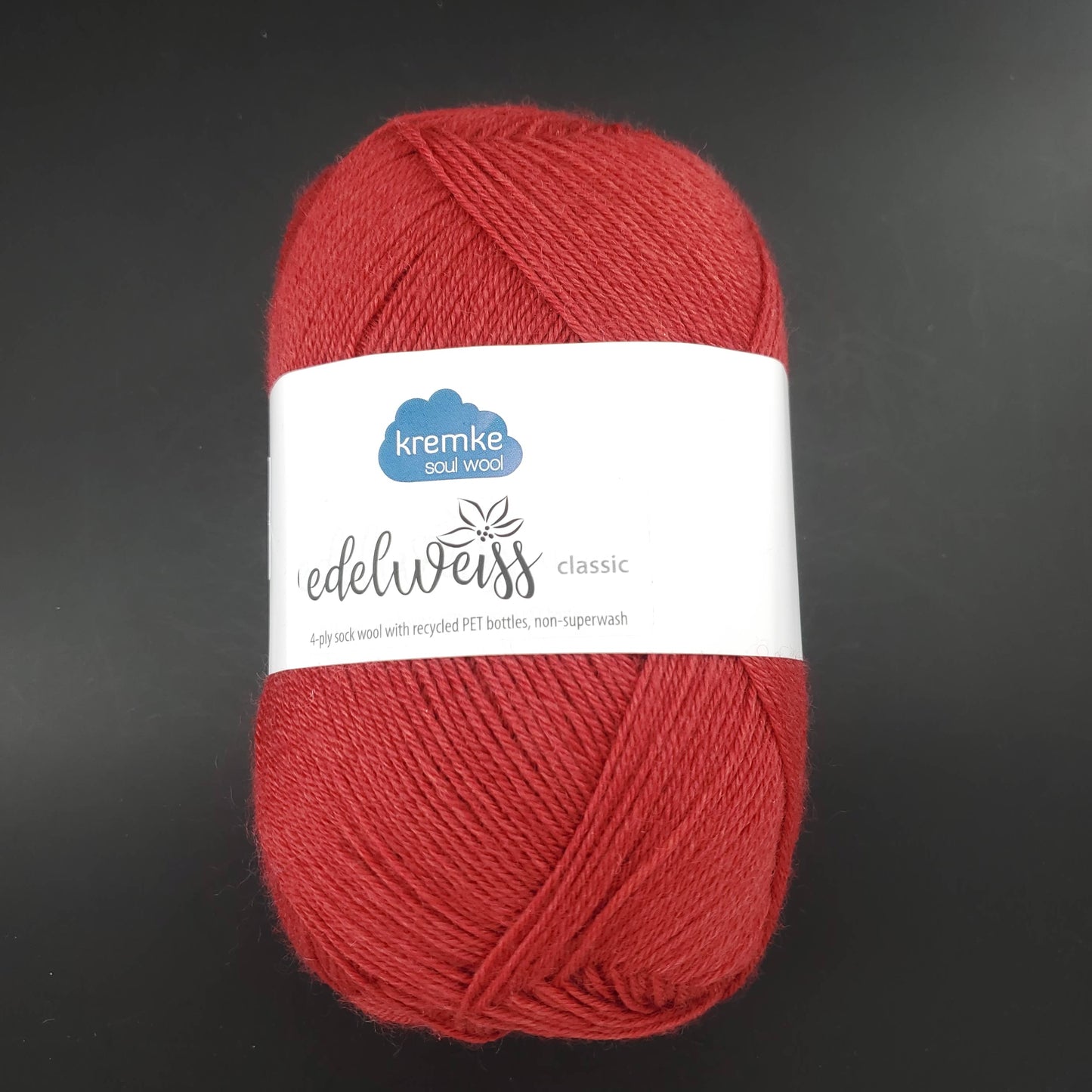 pelote de laine edelweiss classic de marque kremke de coloris 409 rouge pour tricot et crochet sur fond noir
