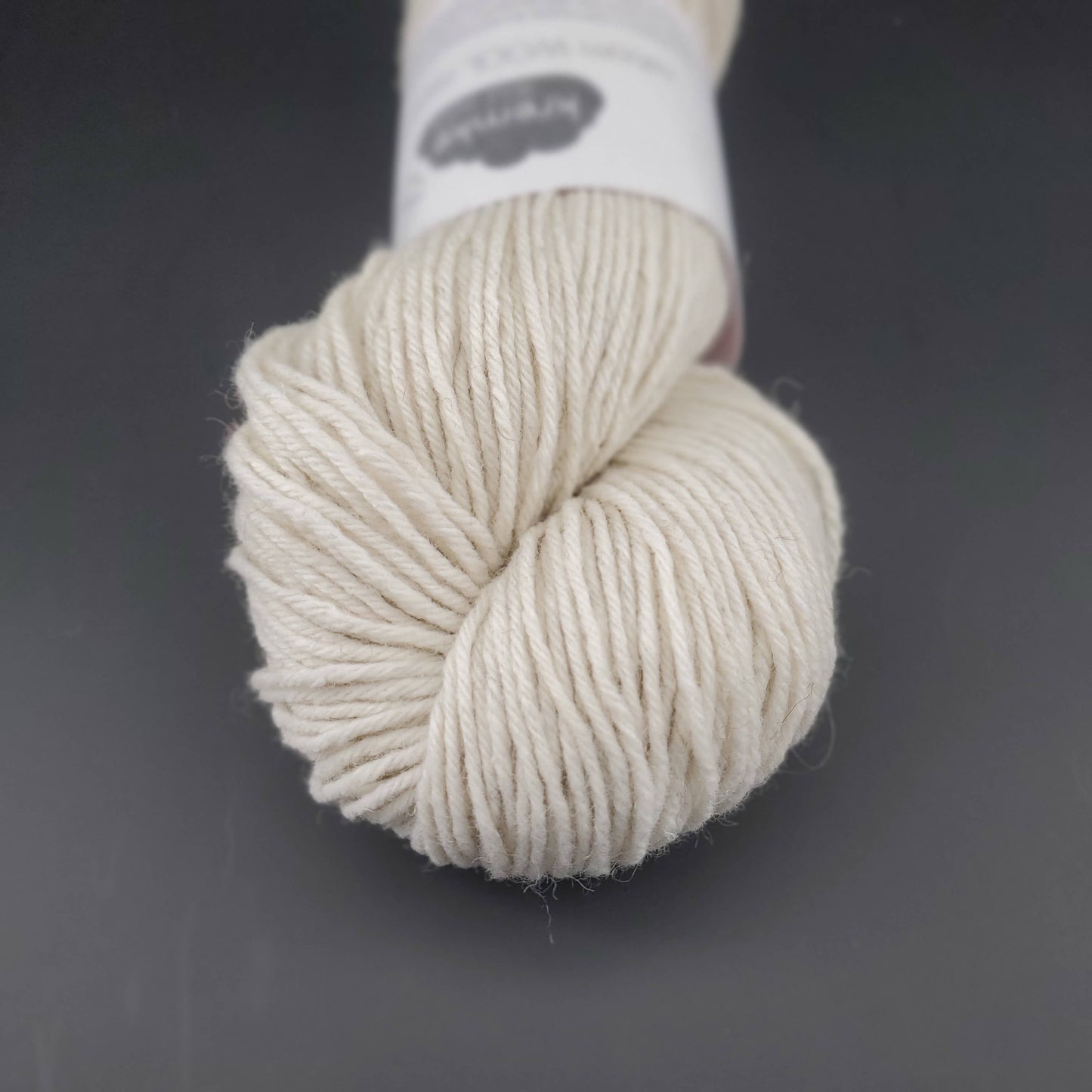 Echeveau de laine Kremke Reborn Wool de couleur 01 natural white, sur fond noir, pour tricot et crochet.