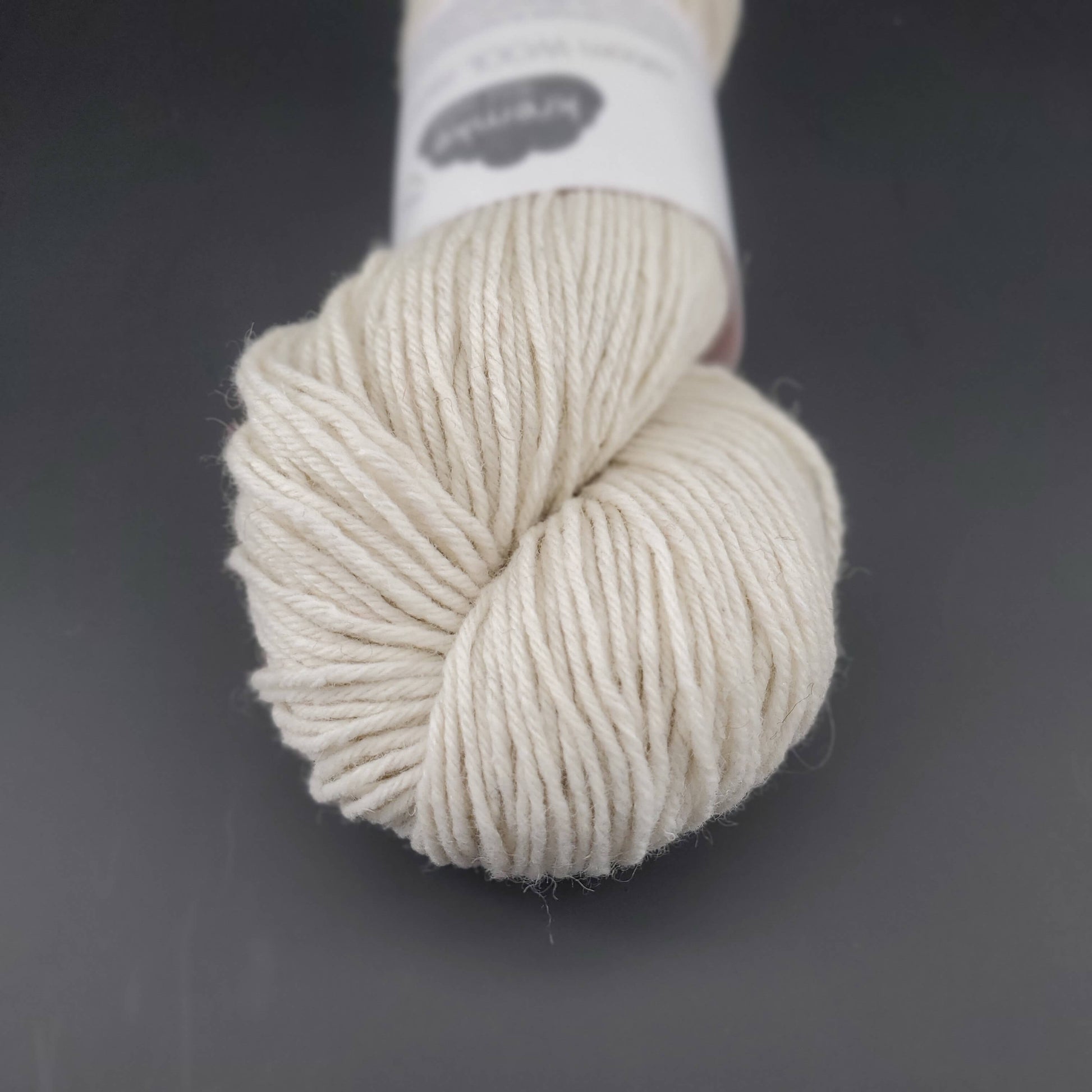 Echeveau de laine Kremke Reborn Wool de couleur 01 natural white, sur fond noir, pour tricot et crochet.