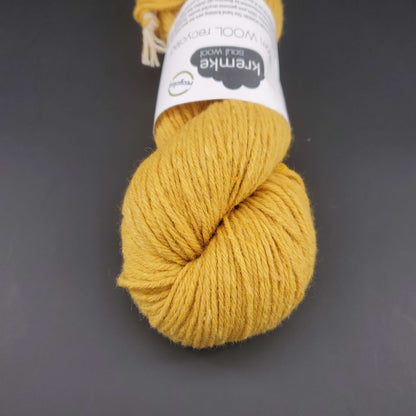Echeveau de laine Kremke Reborn Wool de couleur 06 golden yellow, sur fond noir, pour tricot et crochet.