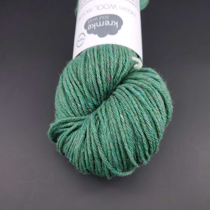 Echeveau de laine Kremke Reborn Wool de couleur 11 emerald, sur fond noir, pour tricot et crochet.