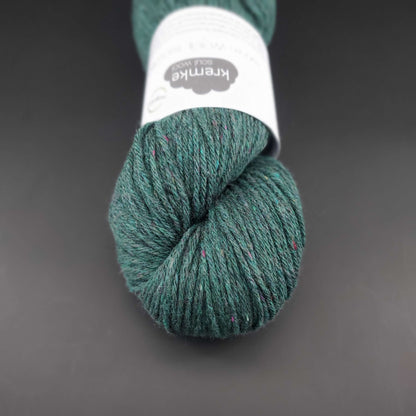 Echeveau de laine Kremke Reborn Wool de couleur 12 dark green, sur fond noir, pour tricot et crochet.