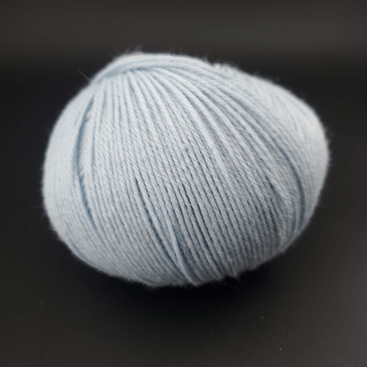 Pelote de laine the merry merino 220 de kremke coloris 21 bleu layette sur fond noir