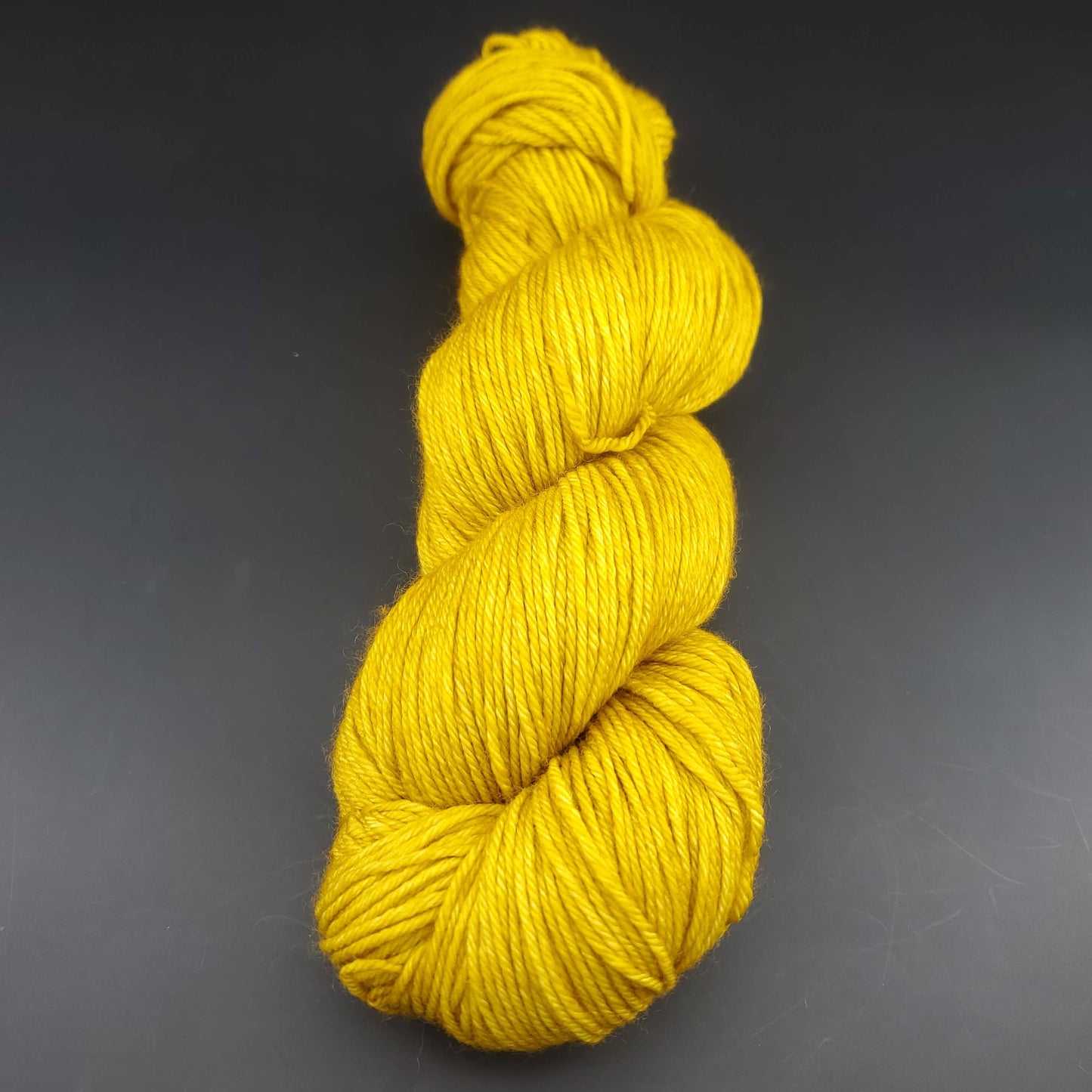 Echeveau de laine Malabrigo Arroyo de couleur 035 franck ochre sur fond noir pour tricot et crochet