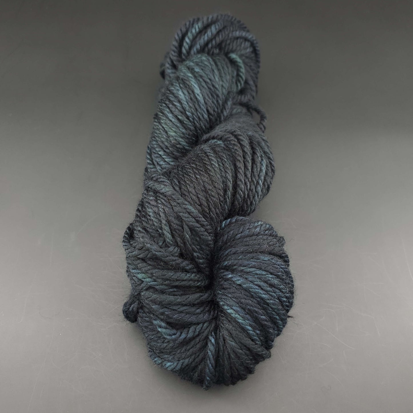 Echeveau de laine Malabrigo Chunky de couleur 020 cypress sur fond noir pour tricot et crochet.