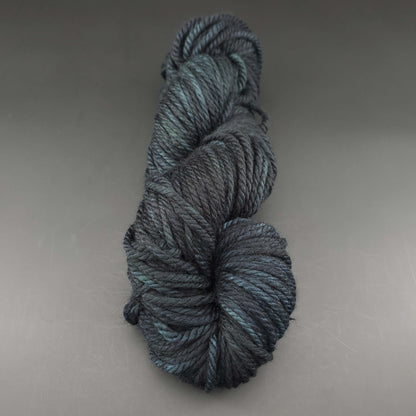 Echeveau de laine Malabrigo Chunky de couleur 020 cypress sur fond noir pour tricot et crochet.