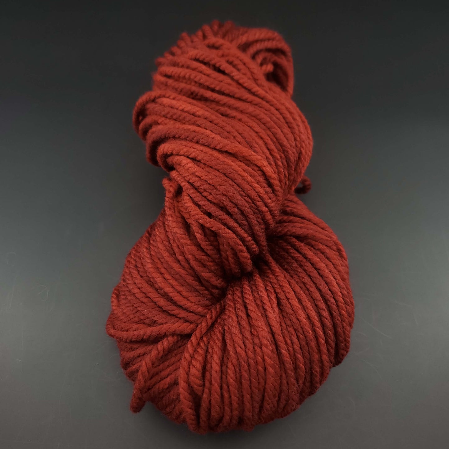 Echeveau de laine Malabrigo Chunky de couleur 041 burgundy sur fond noir pour tricot et crochet.