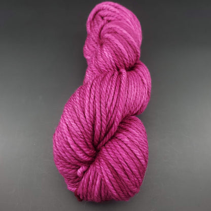 Echeveau de laine Malabrigo Chunky de couleur 148 hollyhock sur fond noir pour tricot et crochet.