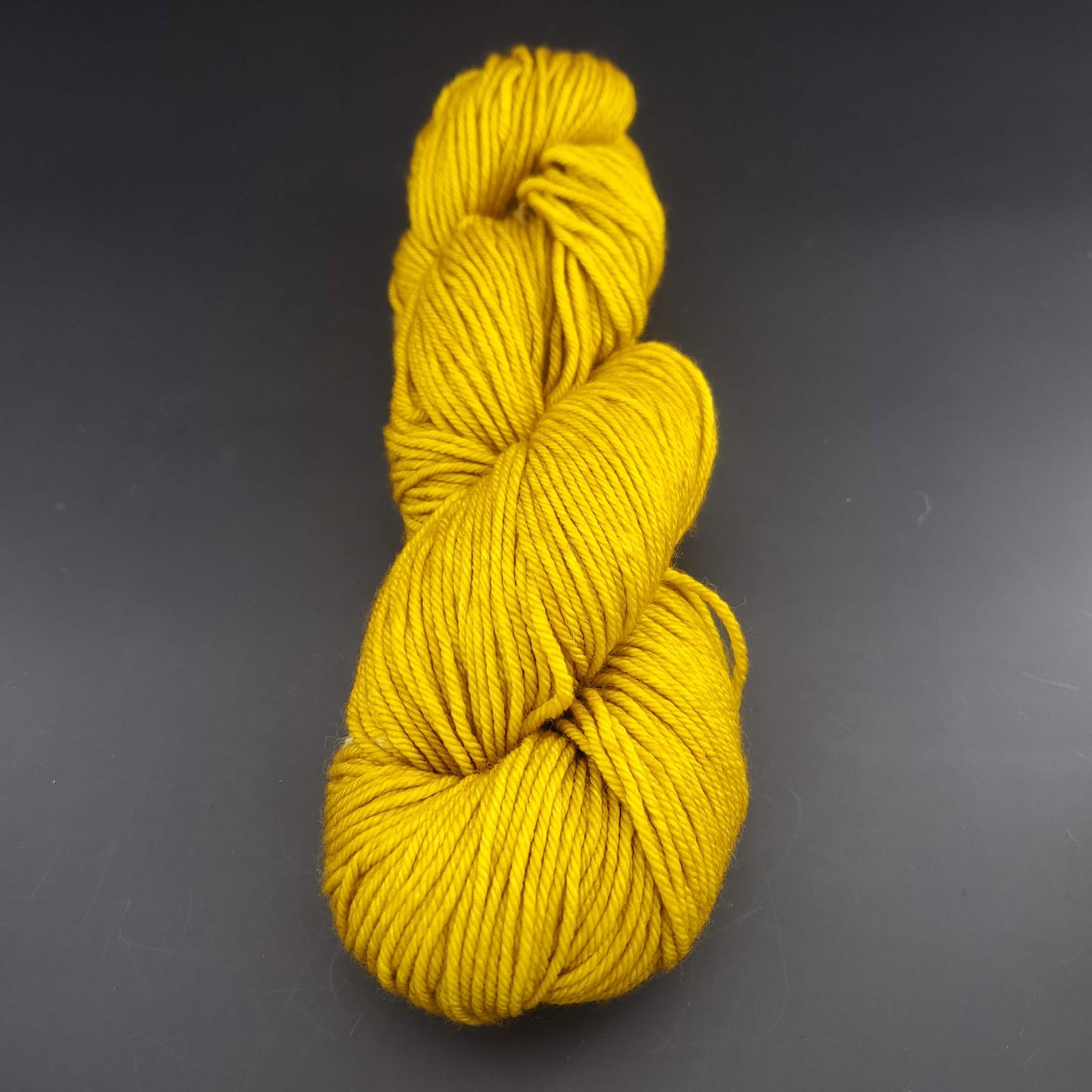 Echeveau de laine Malabrigo Rios de couleur 035 franck ochre sur fond noir pour tricot et crochet.