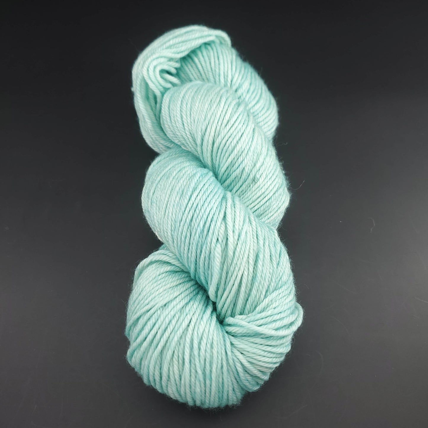 Echeveau de laine Malabrigo Rios de couleur 083 water green sur fond noir pour tricot et crochet.