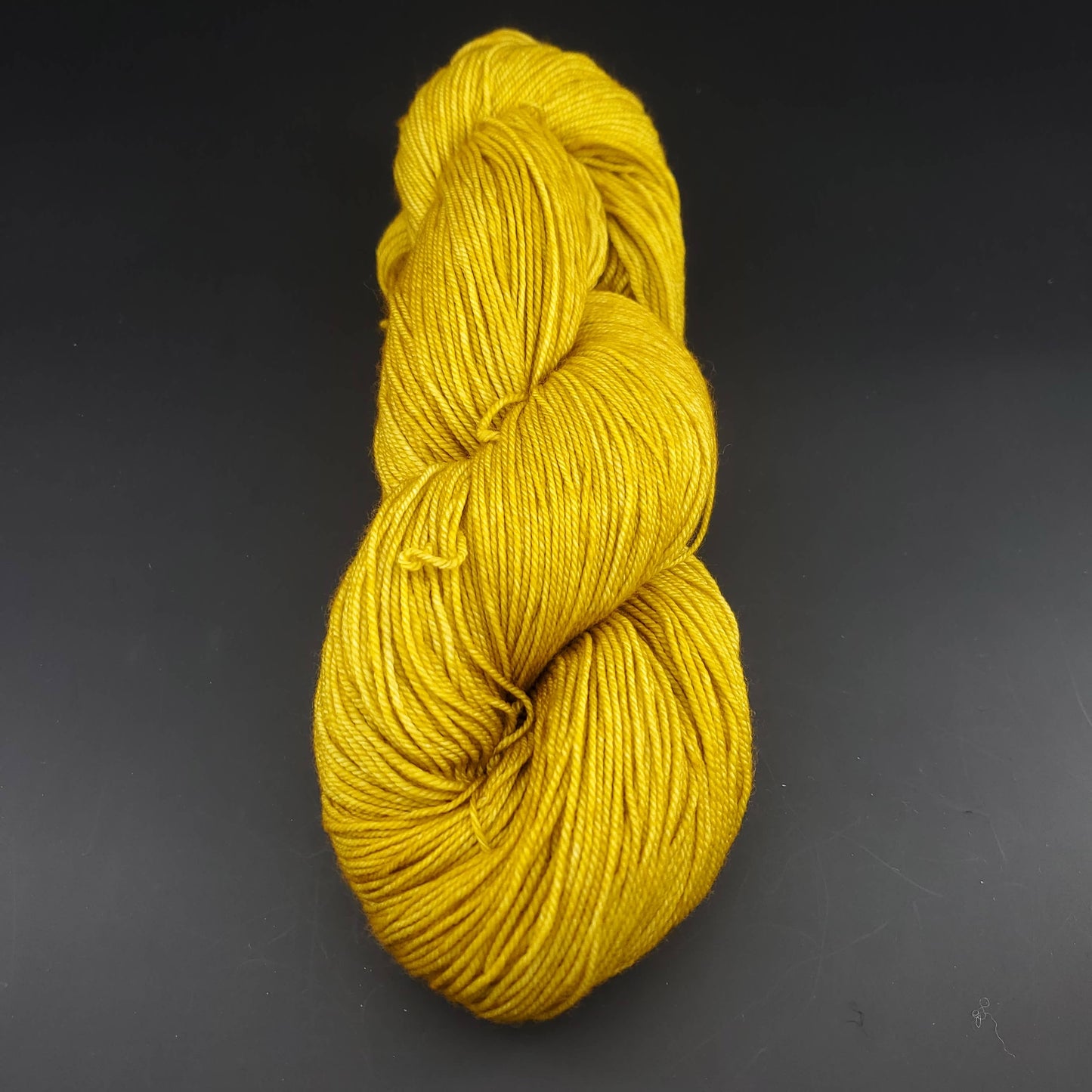 Echeveau de laine Malabrigo Sock de couleur 035 franck ochre sur fond noir pour tricot et crochet.