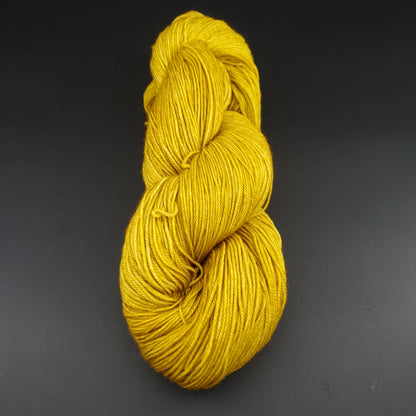 Echeveau de laine Malabrigo Sock de couleur 035 franck ochre sur fond noir pour tricot et crochet.