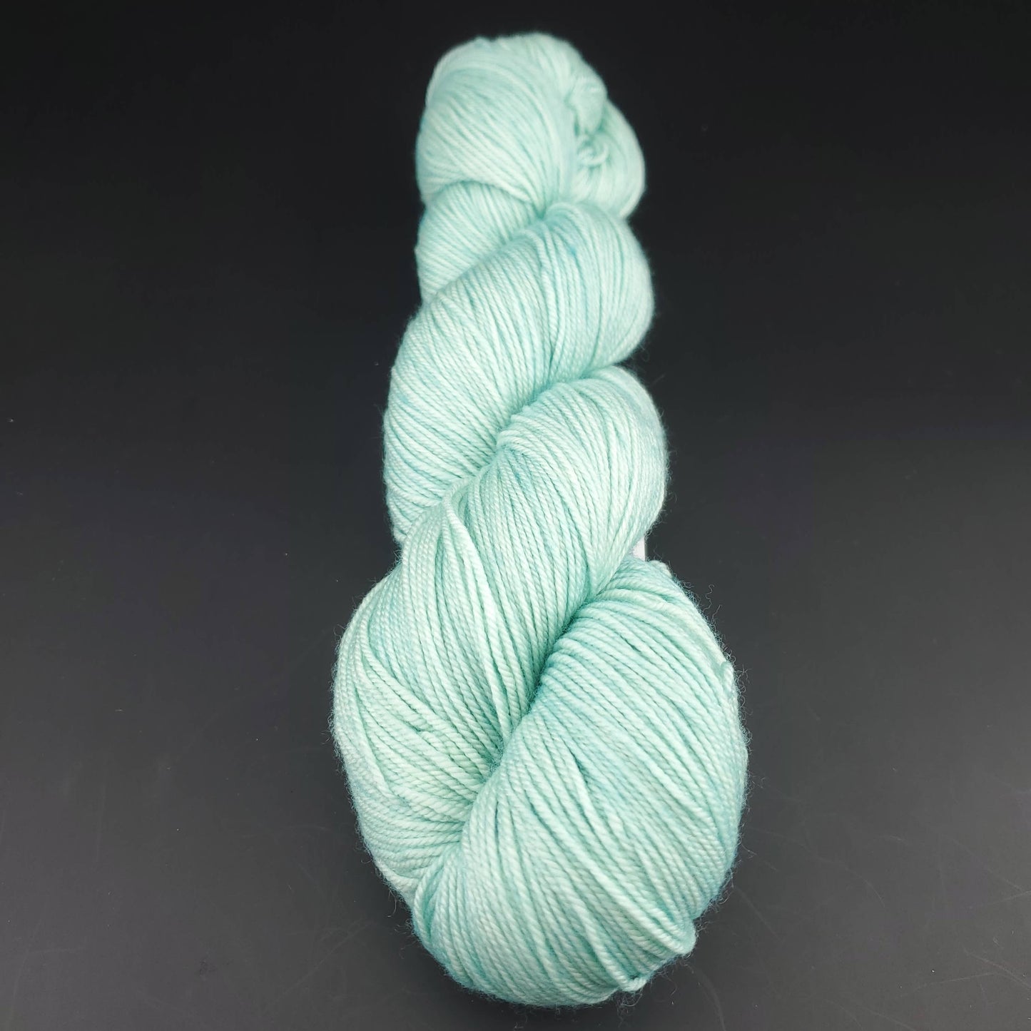 Echeveau de laine Malabrigo Sock de couleur 083 water green sur fond noir pour tricot et crochet.