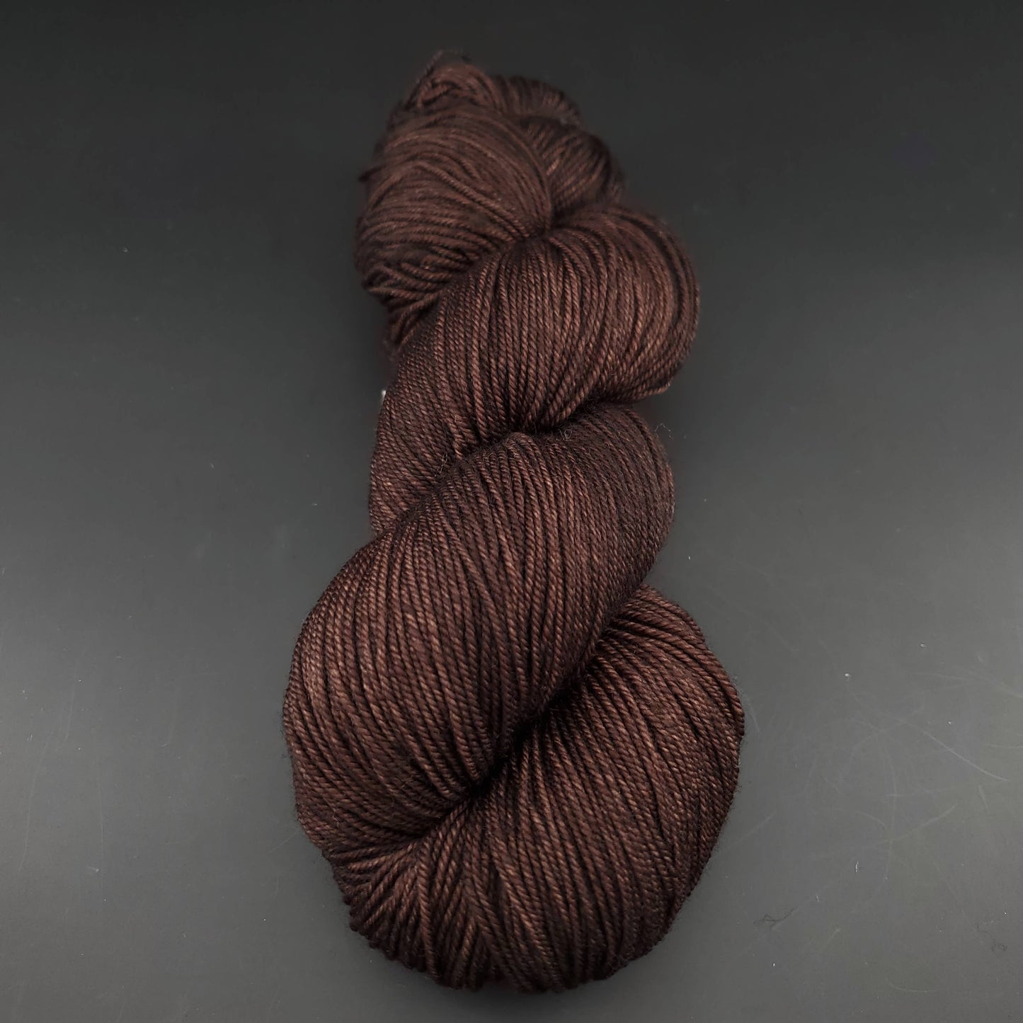 Echeveau de laine Malabrigo Sock de couleur 812 chocolate amargo sur fond noir pour tricot et crochet.