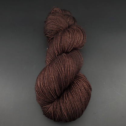 Echeveau de laine Malabrigo Sock de couleur 812 chocolate amargo sur fond noir pour tricot et crochet.
