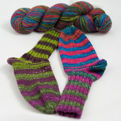 écheveau de laine à chaussettes Lazy Lion, multicolore, marque Kremke et paire de chaussettes tricotées (vert, rose, bleu)